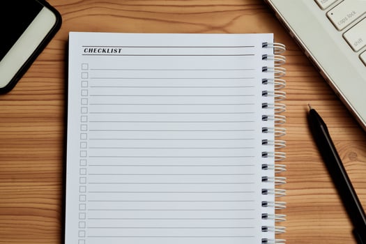 Blank checklist with space for ticks on notepad with laptop, smartphone and pen. photo