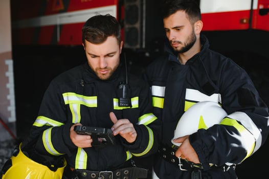 Portrait of two firefighters in fire fighting operation, fireman in protective clothing and helmet using tablet computer in action fighting photo