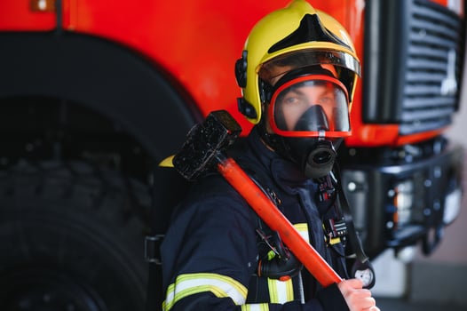 Photo of fireman with gas mask and helmet near fire engine
