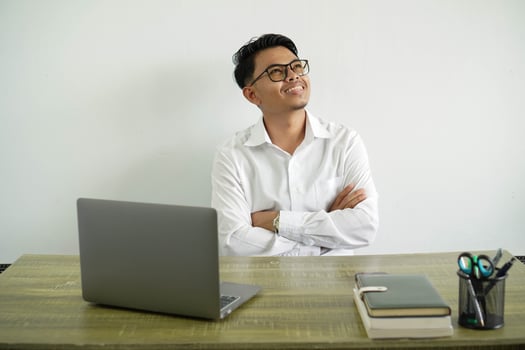 young asian businessman in a workplace looking up while smiling, wearing white shirt with glasses isolated photo