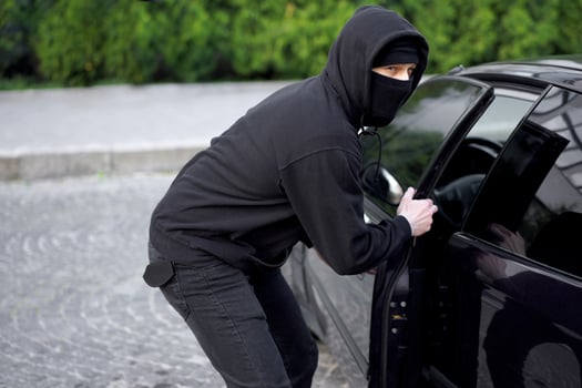 Car thief steal car breaking door criminal job burglar Hijacks  Auto thief black balaclava hoodie trying  break into vehicle screwdriver  Street crime violence gangster robber automobile photo