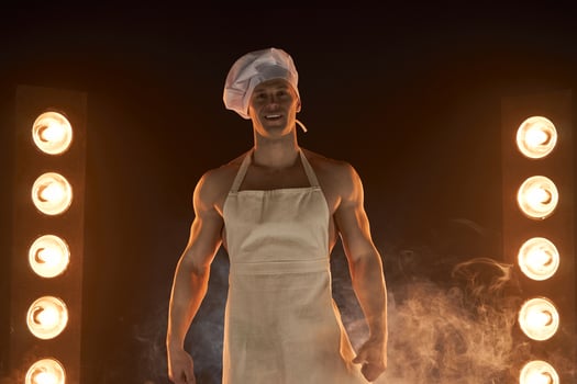 Portrait of muscular chef wearing white apron and cheef hat,  on smoky background photo