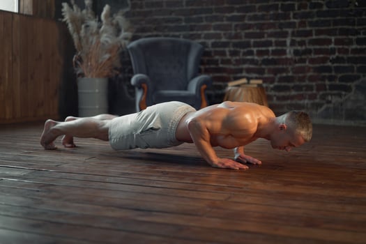 Endurance workout. Muscular man practicing push ups exercise at home interior photo