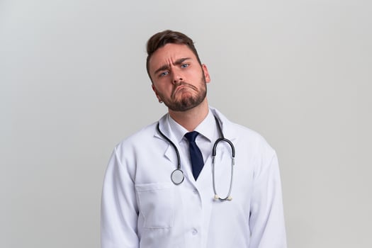 Young handsome modern doctor in a white medical gown stands in the studio on a white background. Student trainee of a medical university. photo