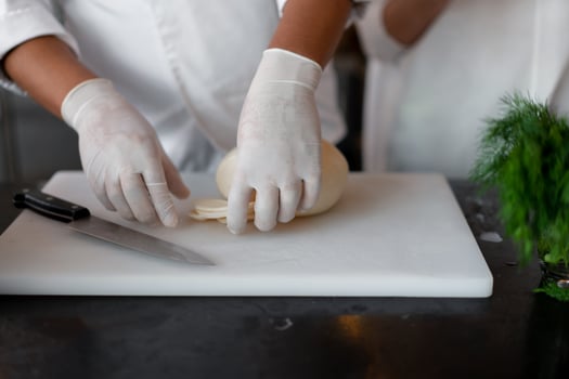 Unrecognizable young African chef standing in professional kitchen in restaurant preparing a meal cheese. photo
