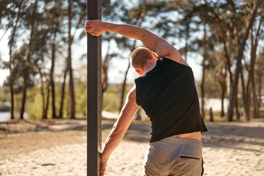 Handsome men outdoor workout cross training morning workout. Stretching arm before exercising outside sports ground nature forest photo