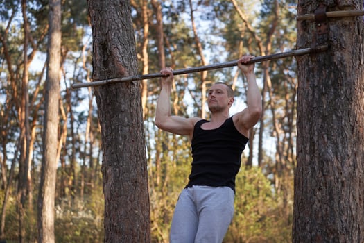 Handsome caucasian men pull-up outdoor workout cross training morning Pumping up arm exercising sports ground nature forest photo