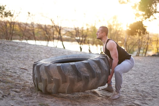 Strong man training workout lifting large tire outdoor DIY gym. photo