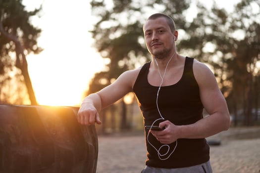 Young adult caucasian athlete listening phone music white headphones after workout. photo