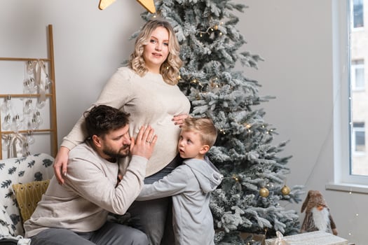 Christmas Family Happiness Portrait of dad, pregnant mom and little son  sitting armchair at home near Christmas tree hug smile photo