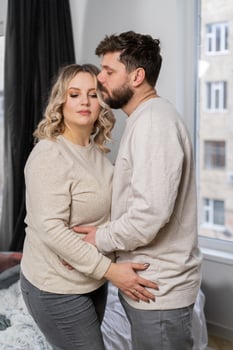 Happy family concept. Husband hug belly pregnant wife standing indoor living room near sofa photo