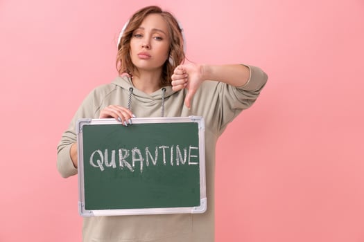 Stay home concept Woman with headphones dressed oversize hoodie holds chalkboard with the words quarantine photo