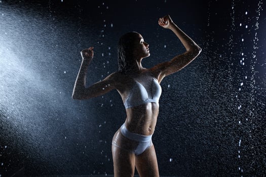 Beautiful young girl in sportswear poses in aqua studio. Drops of water spread about her fitness body. The perfect figure on the background of water splashes photo