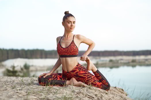 A beautiful Caucasian girl in a sportswear do yoga position on nature against the backdrop of the bright sun. photo
