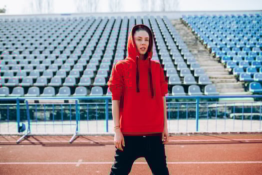 Young sports woman in sweatshirt resting after jogging training on the running track at summer photo