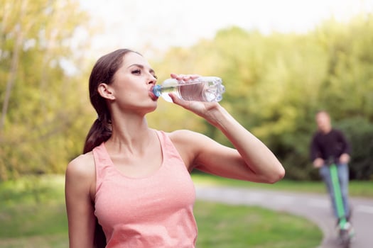 Athletic woman standing running track in summer park drink water after running exercises photo