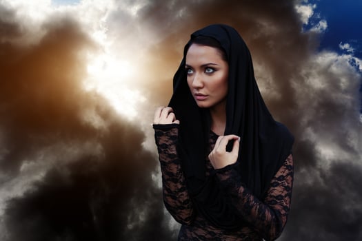 A woman is a prophet sorcerer and a preacher in a black mystical cloak with a hood against a dramatic background... photo