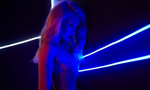 fashion art photo of sexy girl dressed in red in the night-club. Perfect female body with neon lettering on the background