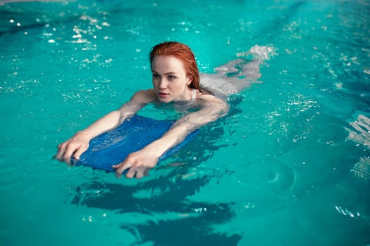 Beautiful young redhead Caucasian girl swims in the indoor swimming pool. Healthy lifestyle. photo