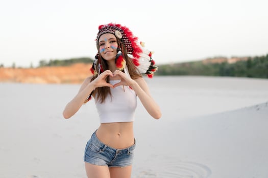 A beautiful young Caucasian girl in a white top on her head is wearing an Indian hat. Roach is in the desert. Happy holiday mood. photo