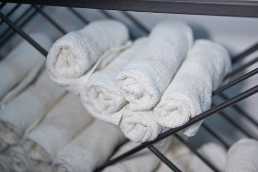 White clean towels rolled up on a roll are stored on shelves in a beauty salon in a barbershop spa. photo