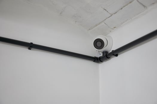 White round cctv camera installed in the corner on a white wall. photo
