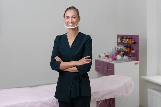 Cosmetology cabinet. Beautician stands in mask and smiles. photo