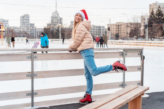 Beautiful lovely middle-aged girl blonde hair warm winter jackets knitted glove stands ice rink background Town Square. Christmas mood lifestyle photo