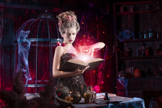 Charming woman witch flowers in hair vintage black dress with book of spell in the old castle. Halloween. Celebration. photo