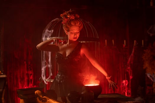 Witch with cauldron. Beautiful young woman conjuring, making witchcraft photo