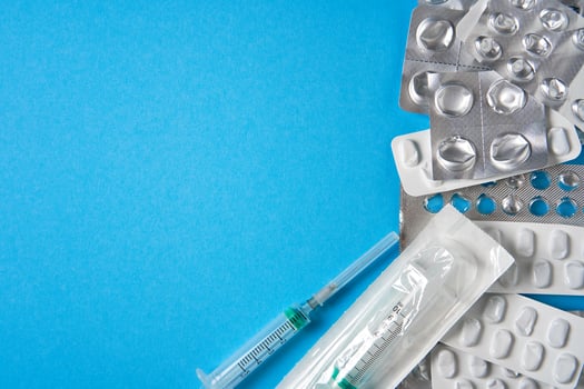 Empty used blisters from tablets silver and white color and pills lie on blue medical background photo