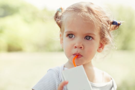 Sunny portrait of a little child drinking from a straw juiceon blurred summer background photo