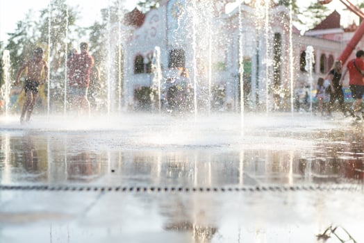 Unrecognizable Happy kids have fun playing in city dry water fountain on hot summer day photo