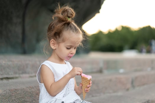 Little caucasian girl 3 years old eats ice cream closeup portrait photo