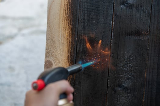 Professional carpenter using old traditional japanese technique. Burning wood planks with gas burner photo