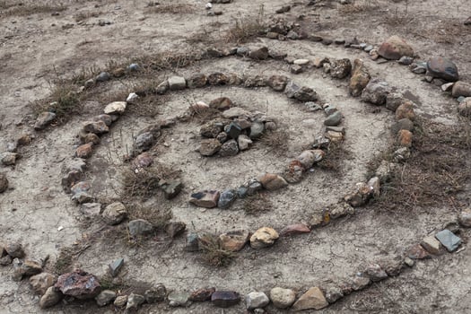 stones laid out on the sand in a spiral like a ritual photo
