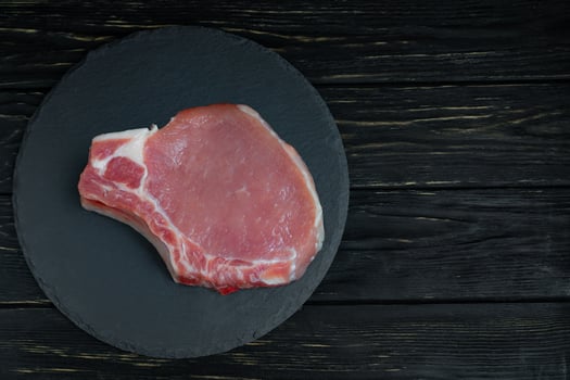 Top view of one pieces raw pork chop steaks on a black stone cutting board. photo