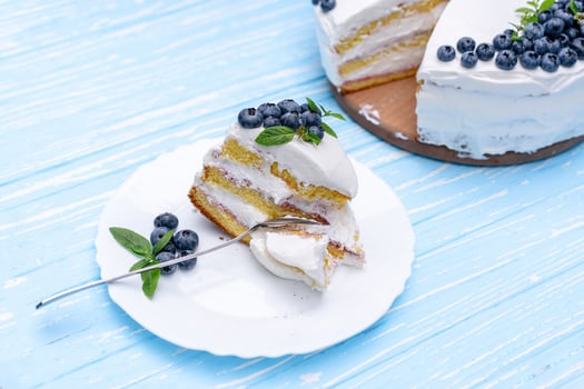 Appetizing cheesecake cake biscuit pillow decorated white cream blueberries and mint stands on wooden blue rustic table photo