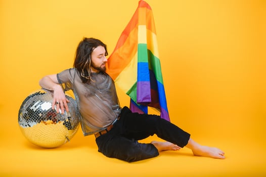 gay man with a gay pride flag smiling and looking away on yellow background. photo