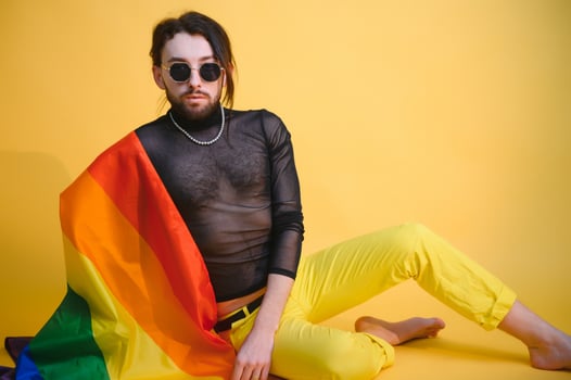 gay man with a gay pride flag smiling and looking away on yellow background photo