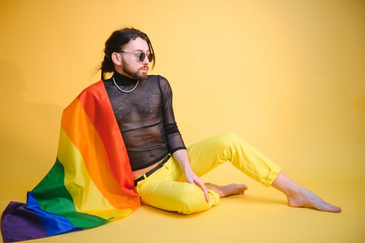 Gay man hold rainbow striped flag isolated on colored background studio portrait. People lifestyle fashion lgbtq concept photo