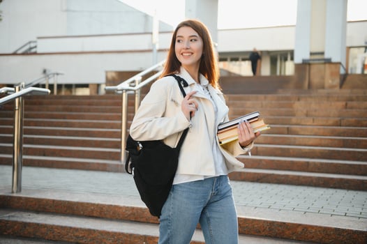 Portrait of a happy female student holding books and looking at camera outdoors photo