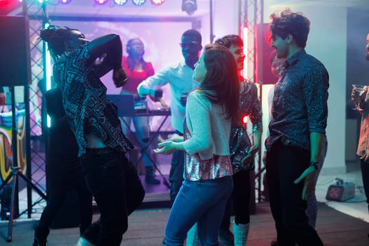 Friends dancing at concert in nightclub, having fun and moving on dancefloor. People partying and enjoying dj live music performance on stage while attending discotheque in club photo