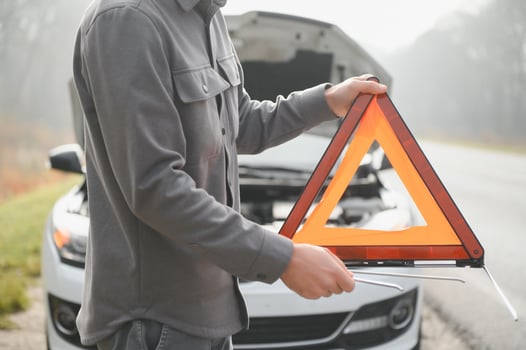 Young upset casual man trying to fix his broken car outdoors. Man waiting for towing service for help car accident on the road. Roadside assistance concept. photo