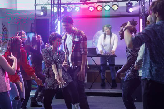 Carefree young woman dancing with friends while celebrating at disco party in nightclub. Clubber showing moves on dancefloor while clubbing and relaxing at discotheque gathering photo