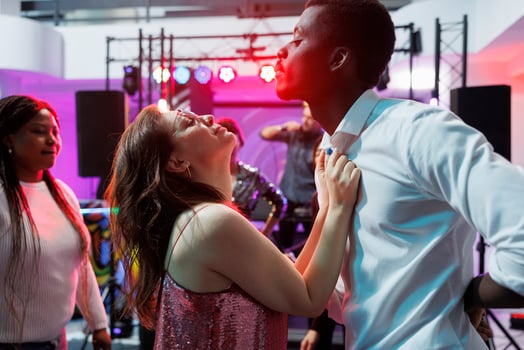 Passionate man and woman dancing and celebrating at nightlife party event. Clubbers couple making energetic moves to live music on crowded dancefloor while clubbing at discotheque photo