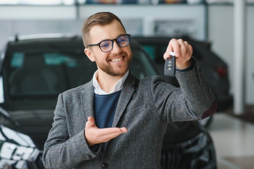 Good looking, cheerful and friendly salesman poses in a car salon or showroom. photo