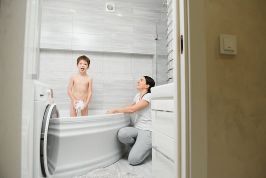 Mother washing little son in bathroom photo