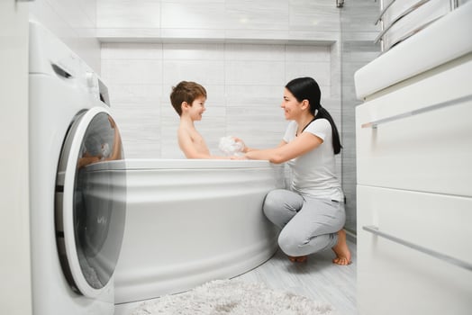 Mother washing little son in bathroom photo