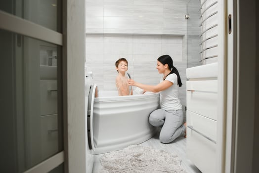 Mother washing little son in bathroom photo